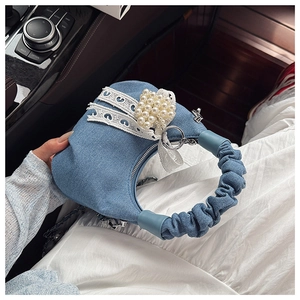 Detail of light blue denim handbag featuring white lace, pearl clusters, and pleated handle
