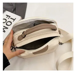 Detail view of woven shoulder bag featuring dual zippers and multiple inner compartments