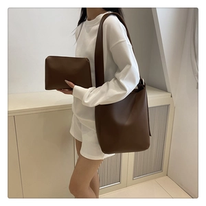 Brown leather tote bag set with matching inner pouch worn by model in minimalist studio