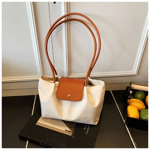 Detail of white tote bag with long brown leather handles and golden round buckle clasp