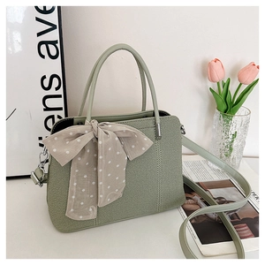 Texture détaillée du sac à main vert sauge avec foulard à pois et anses rondes
