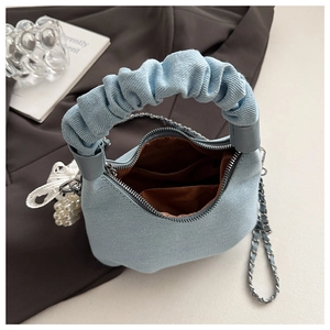Detail of light blue denim handbag featuring a scrunchie handle and silver chain strap