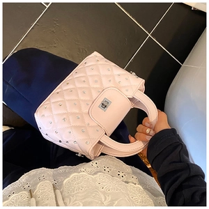 Close-up of pink quilted handbag with silver rhinestones and metal twist lock