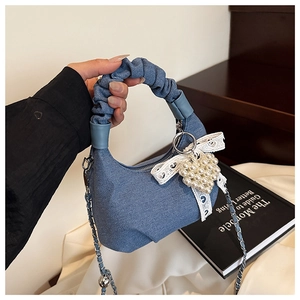 Detail of blue denim pleated handbag with lace bow and pearl heart charm accessory