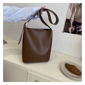 Detail of deep brown leather bucket bag showing sleek texture and large capacity
