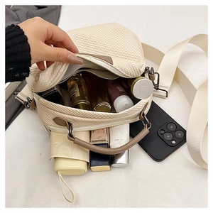 Interior view showing the large capacity of the beige woven crossbody bag with daily items