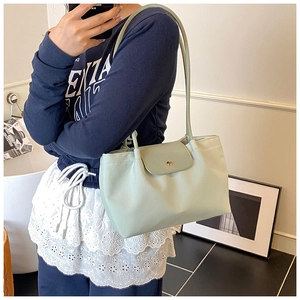 Detail of mint green tote bag with flap closure, long shoulder straps and metallic buckle