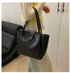 Detail of black tote bag showing white contrast stitching and silver zipper closure