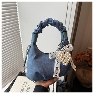 Detail view of ruched denim handbag handle with white lace bow and pearl heart charm