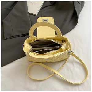 Detailed interior of yellow quilted handbag showing multiple compartments and storage space