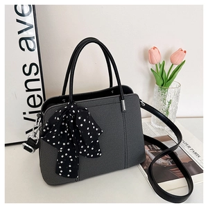 Détail du sac bandoulière gris foncé avec foulard en soie à pois et texture élégante
