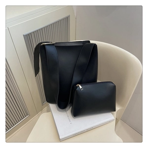 Detail of black matte leather tote bag with a matching pouch on a minimalist chair