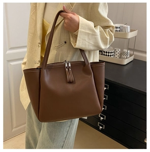 Detailed view of large brown leather tote bag with white contrast stitching for daily use