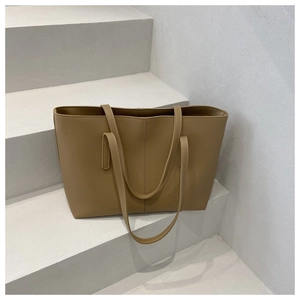 Minimalist khaki PU leather tote bag with clean stitching on white cement steps