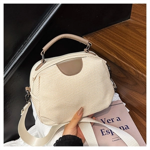 Detail of hand-woven crossbody bag with brown leather handles and wide woven strap