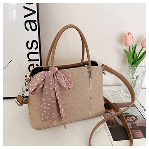 Détail d'un sac à main tressé avec foulard en soie et bandoulière en cuir marron amovible
