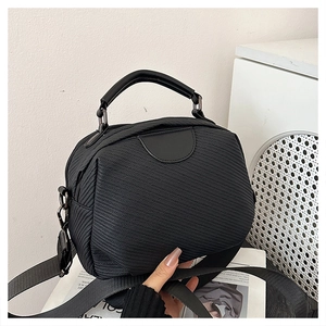 Detail of black twill crossbody bag showing textured fabric and wide shoulder strap