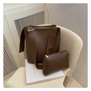 Detail of dark brown matte leather tote set with bucket bag and zipper pouch on a chair