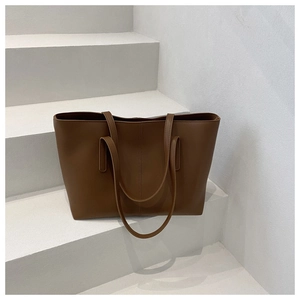 Detail shot of brown leather tote bag with vertical stitching on white stairs