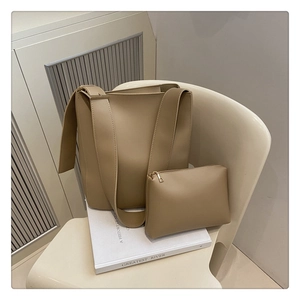 Detail of khaki tote bag set on a chair showing the wide strap and small pouch