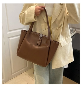 Detailed view of large dark brown leather tote bag showing fine texture and long zipper pullers