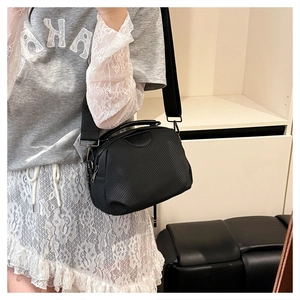 Close-up of black crossbody bag with twill texture and wide strap on model