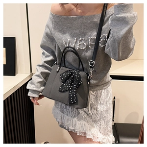 Détail du sac à bandoulière gris avec foulard à pois et design de poignée élégant