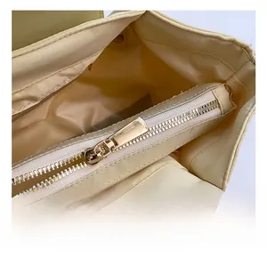Detail view of smooth golden metal zipper and premium beige fabric lining of a handbag