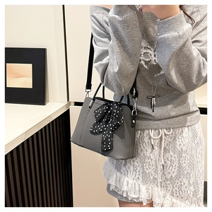 Détail du sac à bandoulière gris avec nœud à pois et surface texturée
