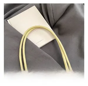 Close-up of pale yellow leather handbag strap on dark gray fabric with a book