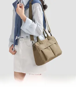 Detail of khaki nylon tote bag with dual front pockets and adjustable shoulder strap