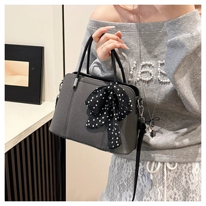 Détail du sac à bandoulière gris foncé texturé avec un nœud à pois noirs élégant
