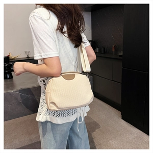 Detail of beige woven crossbody bag showing half-moon shape and wide fabric shoulder strap