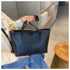 Detail of classic black matte tote bag with vertical stitching and slim handles