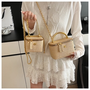 Detail of beige straw handbags with gold circular handles and floral metal logos