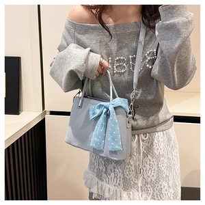 Détail du sac bandoulière bleu clair avec nœud à pois et finitions argentées chic