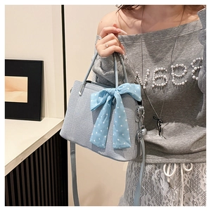 Détail du sac bandoulière bleu clair avec foulard en soie à pois et sangle réglable