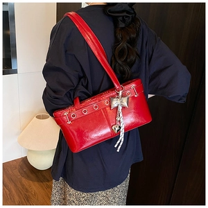 Borsa a spalla rossa con occhielli argentati e ciondolo a fiocco indossata da modella