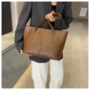 Detail of a deep brown faux leather tote bag with vertical stitching and slim straps