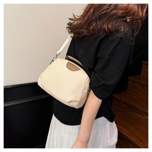 Detail of beige woven crossbody bag with brown leather lid and stylish shoulder strap
