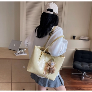 Detail der beige Tote Bag mit Krokodilprägung und süßem Teddybär-Anhänger