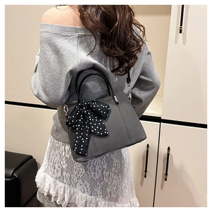 Sac à bandoulière gris minimaliste avec foulard à pois porté par un mannequin femme