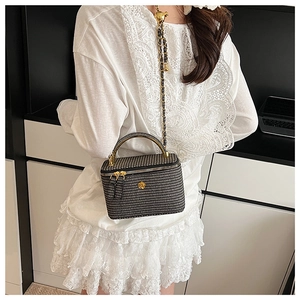 Detail of checkered woven mini bag featuring gold camellia logo and adjustable chain strap