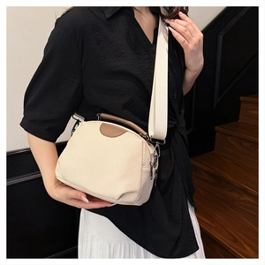 Detail of cream woven shoulder bag with brown leather handles and wide canvas strap