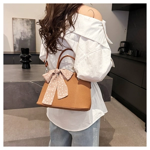 Vue détaillée du sac bandoulière en cuir marron avec un foulard en soie à pois roses