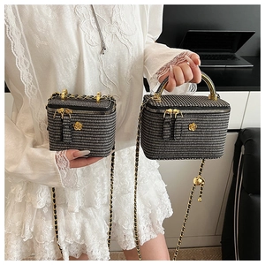 Detail of houndstooth crossbody bags featuring golden camellia charm and chain strap