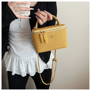 Macro detail of yellow woven mini box bag with golden camellia buckle and chain strap