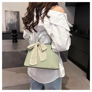 Sac bandoulière vert clair avec foulard à pois et texture tissée porté par le mannequin