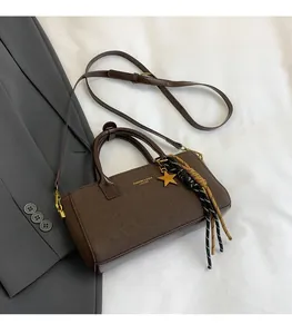 Vue détaillée du sac à main mat marron avec pendentif étoile dorée et pompon tissé