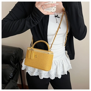 Detailed view of yellow woven box mini bag with golden floral relief and metal handle